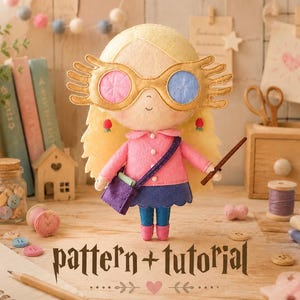 May include: A handmade felt doll with blonde hair, wearing gold-rimmed glasses with pink and blue lenses, a pink coat, and a purple purse. The doll holds a wand and has a blue skirt and blue pants. The text "pattern + tutorial" is at the bottom.