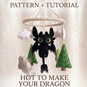 May include: A handcrafted baby mobile with a black dragon, green-eyed, white clouds, green felt trees, and a silver fish. The mobile is suspended from a woven ring. Text reads "PATTERN + TUTORIAL" and "HOT TO MAKE YOUR DRAGON."