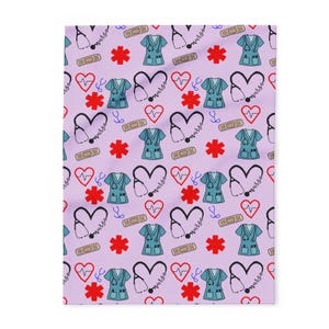 Puede incluir: Una manta lila con un patrón repetido de símbolos médicos. El diseño incluye batas médicas de color verde azulado, estetoscopios, corazones, vendas y estrellas rojas. La palabra "enfermera" está escrita en cursiva.