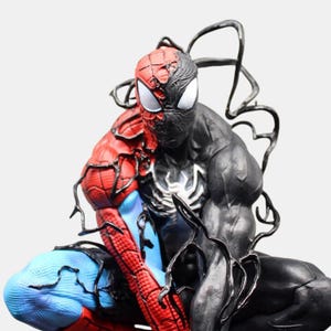 May include: A detailed figurine of Spider-Man split in half, with one side in classic red and blue, and the other in black, resembling Venom. The figure is in a crouching pose, showcasing intricate detailing.