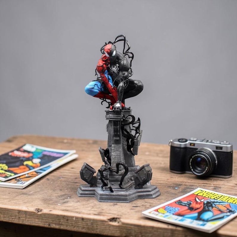 May include: A detailed statue of Spider-Man and Venom in a dynamic pose, perched atop a gray, ornate base. The figure is painted in vibrant red, blue, and black. A vintage camera and comic books are also visible.