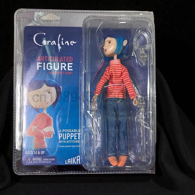 May include: A Coraline articulated figure in a clear plastic package. The doll wears a red and orange striped shirt, blue jeans, and orange boots. The packaging includes the movie title and the text "Ages 14 & Up".