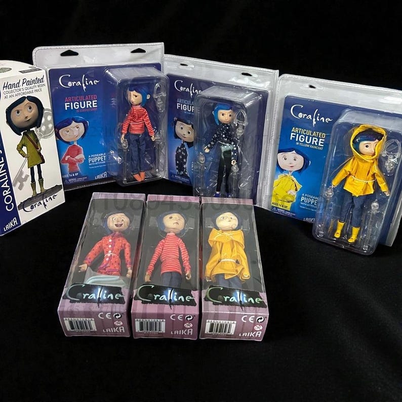 May include: Collection of Coraline articulated figures in various outfits, including a yellow raincoat and a red striped shirt. Each figure is packaged in a clear plastic case with the Coraline logo and the Laika logo.