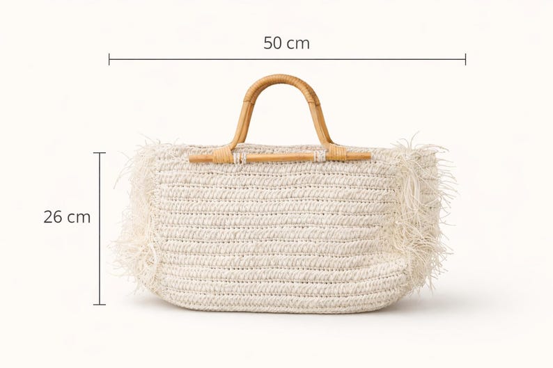 K&ouml;nnte beinhalten: Cremefarbene gewebte Tragetasche mit Bambusgriff. Die Tasche ist 50 cm breit und 26 cm hoch, mit einem Fransenrand. Der Griff ist aus gebogenem, nat&uuml;rlichem Bambus. Ein stilvolles und praktisches Accessoire f&uuml;r den t&auml;glichen Gebrauch.