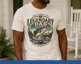 Pode incluir: Camiseta creme com um gráfico com um peixe saltando e as palavras "LEGENDARY DAD". O design inclui o texto "FISHING, FATHERHOOD, LEGACY" e "GUIDE, HERO, TEACHER, PROTECTOR, ROLE MODEL."