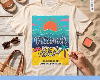 Pode incluir: Uma t-shirt de cor creme com um gráfico de um sol, ondas do oceano, uma palmeira e um guarda-sol de praia. O texto diz Vitamin SEA e DAILY DOSE OF COASTAL SUNSHINE. O design utiliza cores azul, laranja, rosa e amarelo no tecido.