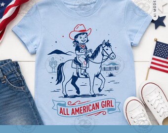 Pode incluir: Uma t-shirt azul claro com uma estampa gráfica de uma pessoa com chapéu de cowboy e jardineiras montada a cavalo. O design inclui um cacto, montanhas e uma cerca, com o texto ALL AMERICAN GIRL impresso numa faixa na parte inferior.