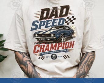 Pode incluir: Camiseta creme com um gráfico de um carro azul clássico e o texto "DAD SPEED CHAMPION". O design inclui bandeiras de corrida e a frase "Built Different. Driven Forever."