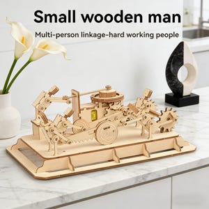 May include: A wooden mechanical model kit with gears, levers, and a small wooden man design. The kit is made of light-coloured wood and features the text "Small wooden man" and "Multi-person linkage-hard working people".