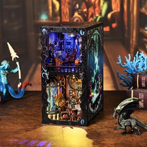 Peut inclure: Un diorama miniature détaillé et éclairé d'une scène fantastique, avec un intérieur à plusieurs niveaux avec des meubles et une décoration. L'extérieur est noir avec des sculptures ornées et une illustration verte et bleue. Petites figurines d'un dragon et d'une créature marine à proximité.