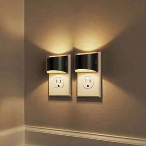 Puede incluir: Una taza de cerámica blanca con un asa negra y el texto "But First, Coffee" en negrita negra. La taza está sobre un fondo neutro, resaltando su diseño simple.