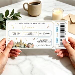 May include: A rectangular boarding pass ticket with gold borders and blue accents. The text reads: PACK YOUR BAGS MUM, WE'RE GOING TO Vienna. PASSENGER: THE BEST MUM EVER, DEPARTING FROM: PARIS INTERNATIONAL, DATE 12TH FEBRUARY 2027. MESSAGE: HAPPY BIRTHDAY MUM! WE CAN'T WAIT TO EXPLORE VIENNA WITH YOU! FROM CLLIE & KIM.