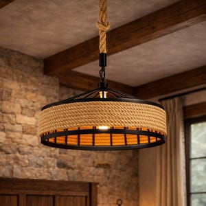 May include: A rustic pendant light with a woven rope shade and a black metal frame hangs above a wooden bed. The light is suspended from a thick rope and illuminates a cozy bedroom setting. The room features a stone wall and wooden beams.