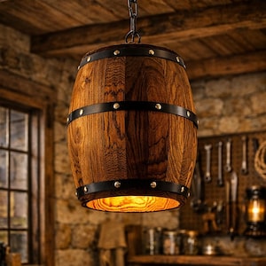 Peut inclure: Un luminaire suspendu en forme de tonneau en bois, avec des bandes et des rivets en métal noir. La lumière est suspendue à une chaîne dans un atelier rustique. La lumière chaude brille du bas du tonneau.