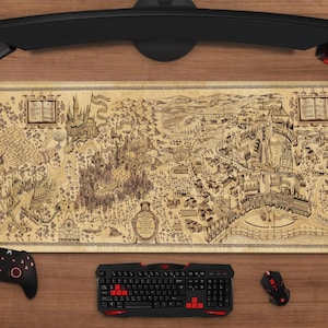 May include: A large rectangular desk mat featuring a detailed map design with text. The mat is beige with a brown map illustration. A black keyboard, mouse, and controller are visible. A curved monitor and headset are also present.