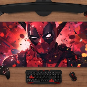 May include: A rectangular Deadpool-themed mousepad featuring a vibrant illustration of the character in a red and black color scheme. The mousepad is surrounded by a keyboard, mouse, controller, and headset on a wooden surface.