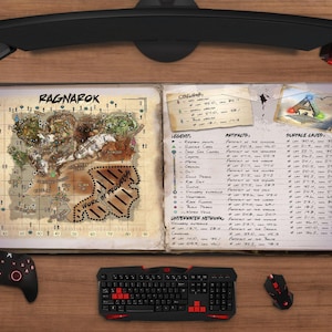 May include: A gaming setup featuring a detailed map labeled "RAGNAROK" in an open book, alongside a black keyboard, mouse, and controller. The map shows a "WORK IN PROGRESS" area. A headset and monitor are also visible.