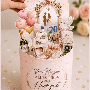 May include: A pink and gold wedding-themed pop-up card with a floral arch, cake, champagne, and heart-shaped balloons. The card features the text "Von Herzen Alles Liebe zur Hochzeit".