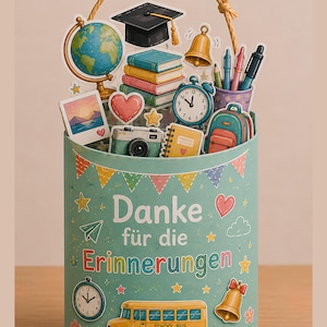 May include: A light blue cylindrical container with a rope handle, featuring the text "Danke für die Erinnerungen". It is decorated with school-themed cutouts including a globe, books, a graduation cap, a bell, a camera, and a yellow school bus.