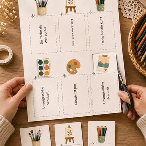 May include: A printable sheet of rectangular cards featuring illustrations of art supplies like paintbrushes, palettes, and easels. Each card contains German text including phrases like Du machst die Welt bunter, Mit Farbe und Herz, and Unvergessliche Schulzeit, with dashed lines for cutting.