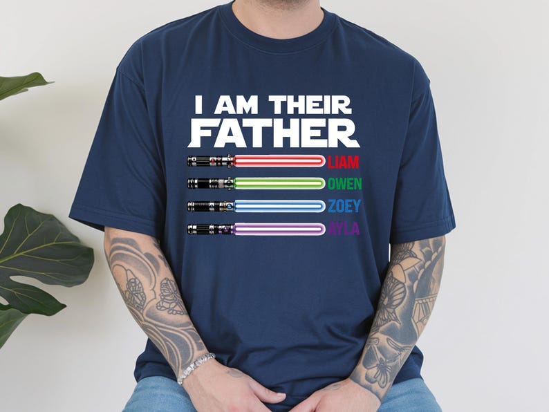 May include: Navy blue t-shirt with the text "I AM THEIR FATHER" in white. Below the text are four lightsabers with the names Liam, Owen, Zoey, and Ayla. The lightsabers have red, green, blue, and purple blades.