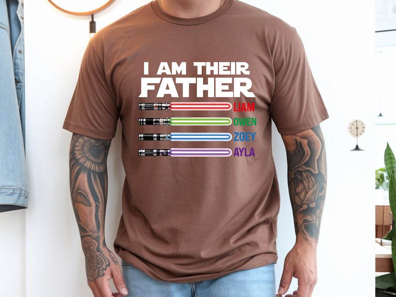 May include: A brown t-shirt with the text "I AM THEIR FATHER" and four colored lightsabers. Each lightsaber has a name: Liam, Owen, Zoey, and Ayla. The lightsabers are red, green, blue, and purple.