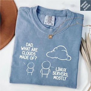 May include: A blue Comfort Colors t-shirt with the text "DAD, WHAT ARE CLOUDS MADE OF? LINUX SERVERS, MOSTLY" in white. The shirt features a cloud graphic and stick figures. A gold necklace is draped across the shirt.