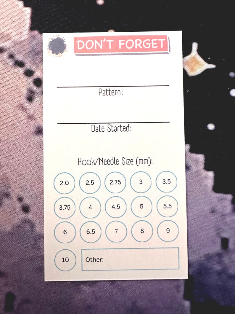 K&ouml;nnte beinhalten: Eine wei&szlig;e Karte mit dem Text "DON'T FORGET" in rosa Schrift. Die Karte hat Platz zum Aufschreiben des Musters, des Startdatums und der Haken-/Nadelgr&ouml;&szlig;e. Es gibt Kreise mit Zahlen von 2,0 bis 10,0 in Millimetern.