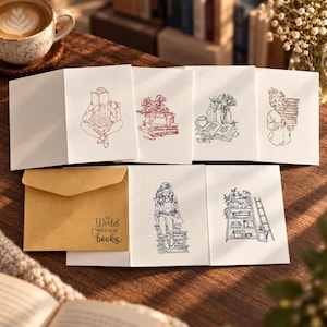 May include: A set of white greeting cards featuring black and red line art illustrations of people reading, stacks of books, and flowers. One kraft paper envelope is included, printed with the text, The World Needs More Books.