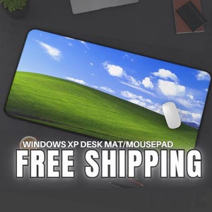 Könnte beinhalten: Rechteckige Schreibtischunterlage/Mauspad mit dem ikonischen Windows XP-Hintergrund: ein grüner Hügel unter blauem Himmel mit weißen Wolken. Eine weiße Computermaus liegt auf der Matte. Text: "WINDOWS XP DESK MAT/MOUSEPAD".