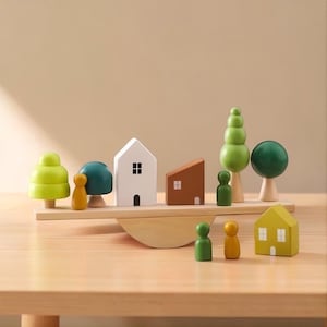 Puede incluir: Un juguete de equilibrio de madera con casas, árboles y figuras en miniatura de varios colores. El conjunto incluye una casa blanca, una casa marrón y una casa amarilla, junto con figuras verdes y amarillas. El juguete está diseñado para equilibrarse sobre una base de madera.