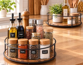 Puede incluir: Dos especieros giratorios de metal negro con bases de madera y frascos de vidrio. Los frascos tienen tapas de madera y etiquetas negras con texto como Olive Oil, Vinegar, Oregano, Paprika, Black Pepper, Sea Salt y un molinillo de madera.
