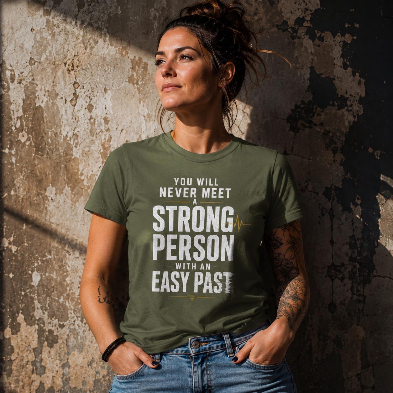 Frau trägt olivgrünes T-Shirt mit weißem Statement-Schriftzug, lehnt an Wand