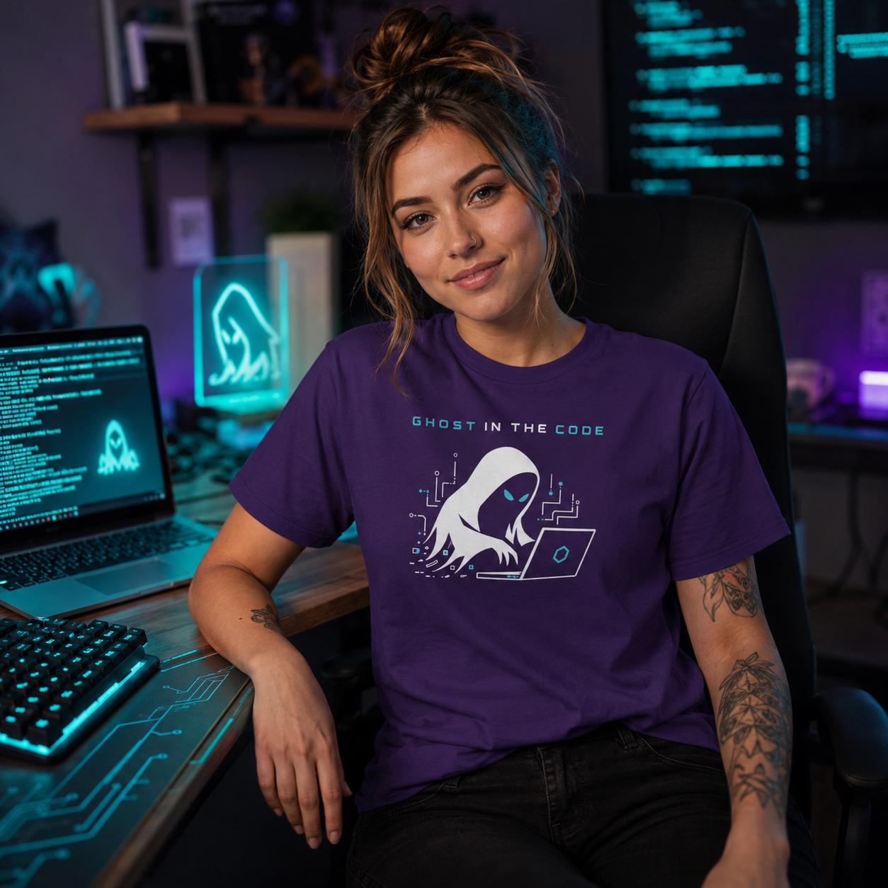 Frau sitzt in lila Ghost in the Code T-Shirt an PC-Arbeitsplatz mit Technik im Hintergrund