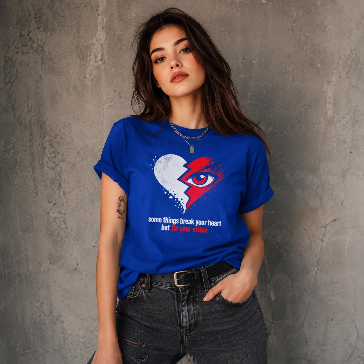 Frau in blauem Unisex T-Shirt mit aufgedrucktem gebrochenem Herz, Auge und Schriftzug posiert vor neutralem Hintergrund