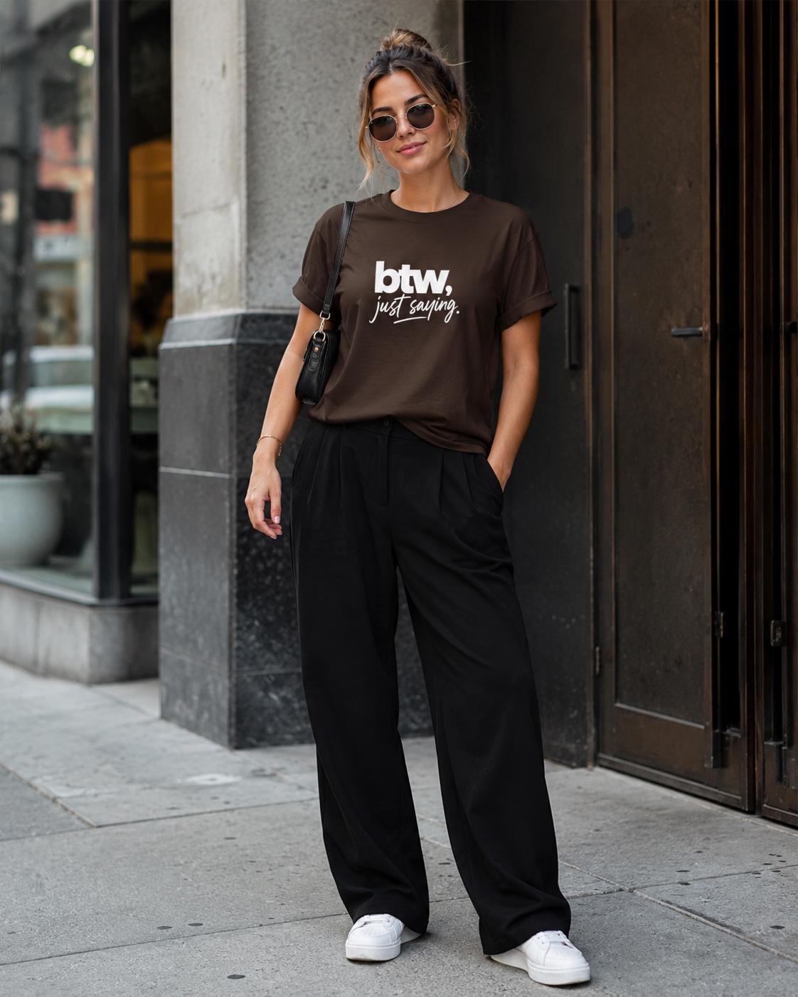 Person steht draußen in braunem T-Shirt mit weißem 'btw, just saying.' Aufdruck und schwarzer Hose