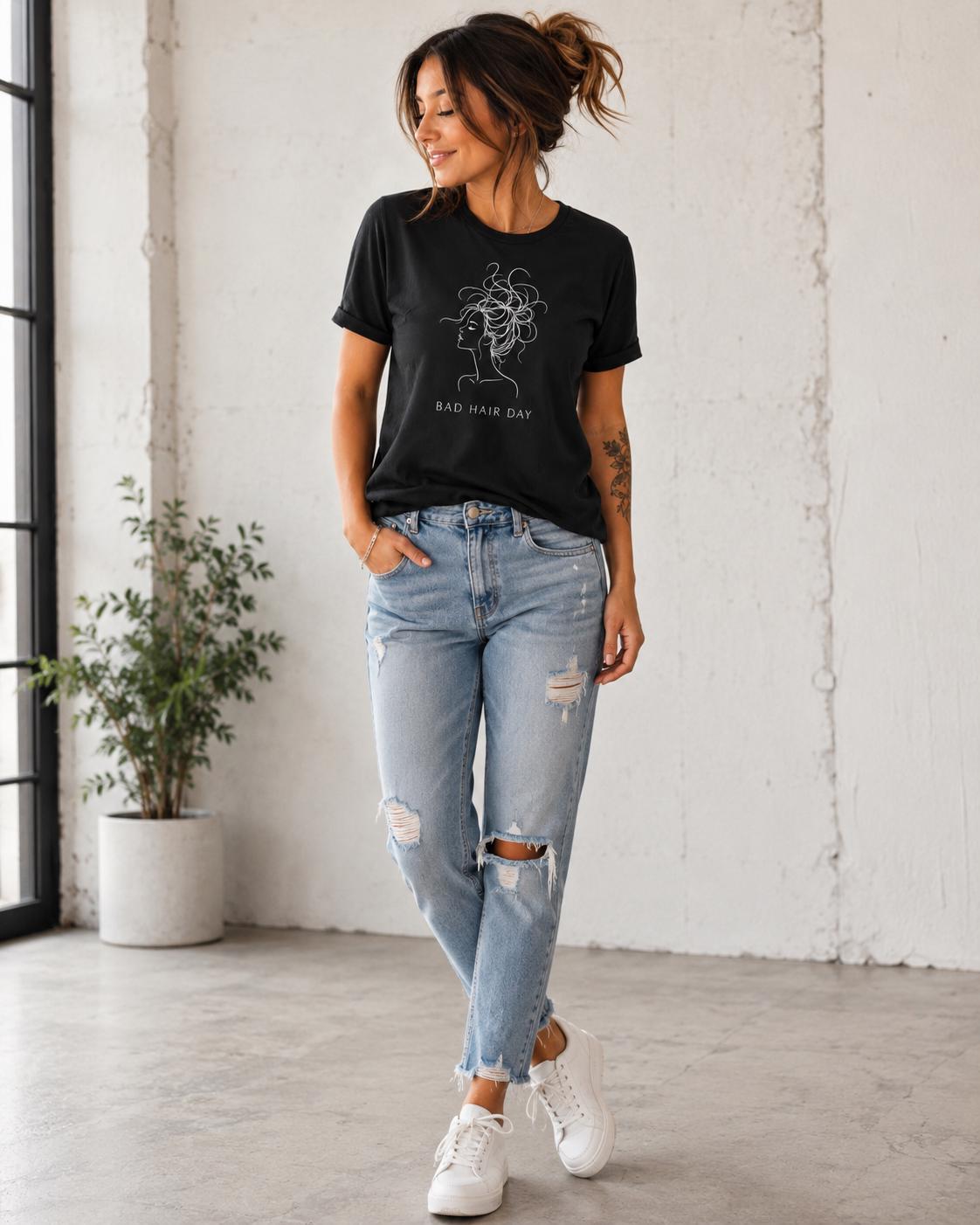 Frau im schwarzen T-Shirt mit Line Art Frisur Motiv und Bad Hair Day Schriftzug steht locker vor weißer Wand