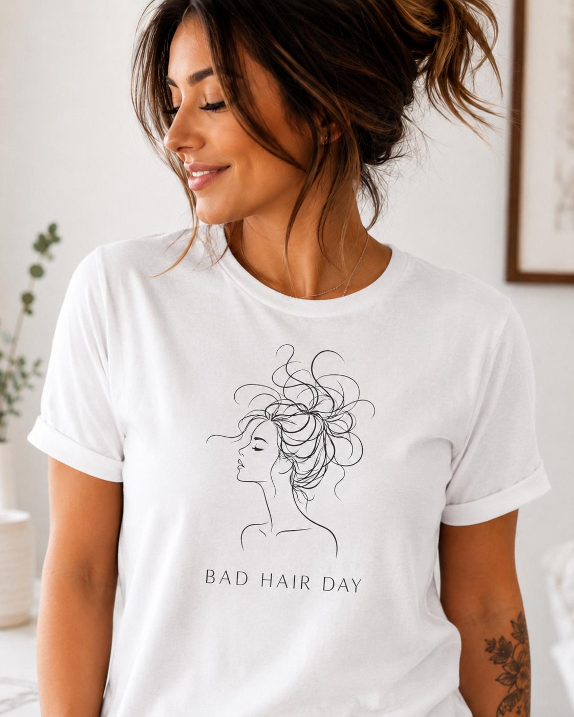 Frau in weißem T-Shirt mit schwarzem Line Art Motiv einer stilisierten Frau und dem Schriftzug Bad Hair Day lächelt nach rechts