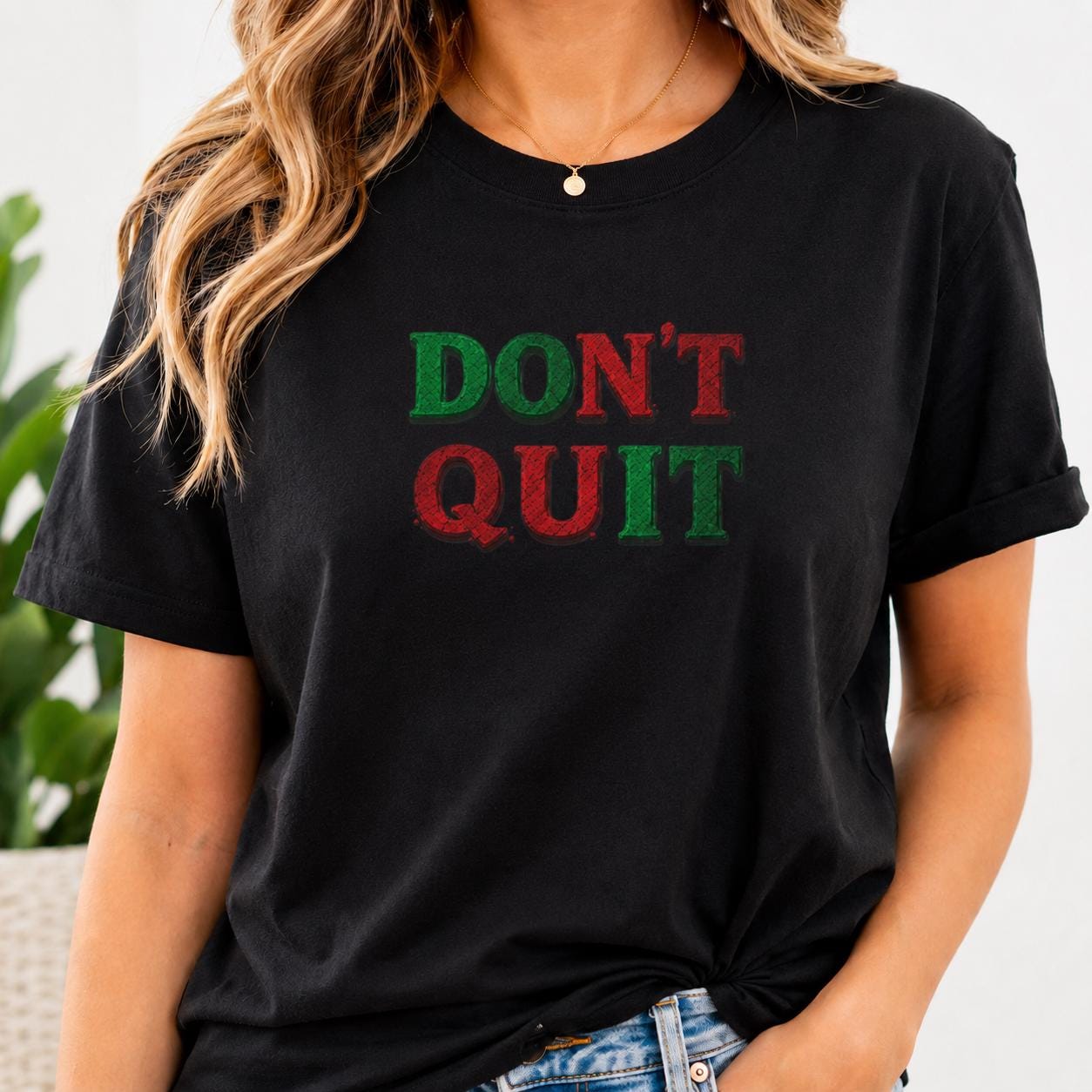 Schwarzes T-Shirt mit rotem und grünem ‚DON’T QUIT‘ Schriftzug auf der Brust getragen von Person