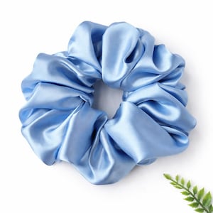 Peut inclure: Un chouchou en satin bleu clair. Cet accessoire pour cheveux est fait d'un tissu doux et brillant, froncé pour créer un effet volumineux et froissé. Le chouchou est de couleur unie et convient à diverses coiffures.