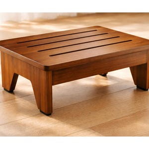 May include: A white ceramic mug with a black handle and the text "But First, Coffee" in a bold, black font. The mug is set against a blurred background, suggesting a cozy setting.