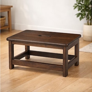 May include: A dark brown wooden step stool with a rectangular top and a handle cutout. The stool has four sturdy legs and a lower support frame. The wood grain is visible, and the stool appears to be well-constructed.