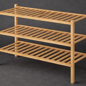 May include: A three-tiered shoe rack made of light-colored wood. The rack has a rectangular shape with slatted shelves and vertical supports. The natural wood finish gives it a simple, functional design, suitable for organizing footwear.