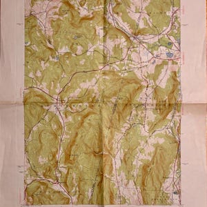 Könnte beinhalten: Eine alte topografische Karte eines ländlichen Gebiets mit Höhenlinien, Straßen und Ortsnamen. Die Karte ist auf gealtertem Papier mit einem beigen Farbton gedruckt. Der Text weist auf den Ursprung der Karte vom US-Innenministerium hin.
