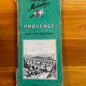 May include: Vintage Michelin travel guide for Provence, France, featuring a green cover with the Michelin logo and the text "PROVENCE." The guide includes a black and white illustration of a bridge and text in French.