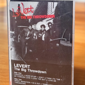 May include: A vintage cassette tape for the album "The Big Throwdown" by Levert. The cover features a black and white photo of the band members. The tracklist includes songs like "Casanova" and "My Forever Love".