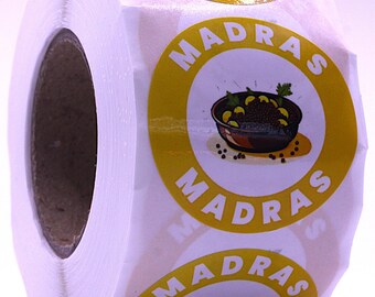 Puede incluir: Un rollo de etiquetas adhesivas circulares con un borde amarillo y la palabra MADRAS impresa en letras mayúsculas blancas. Cada etiqueta muestra una ilustración central de un cuenco marrón oscuro con comida y hierbas verdes.