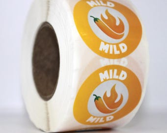 Puede incluir: Un rollo de etiquetas adhesivas con un diseño ovalado de borde amarillo y centro blanco. Cada etiqueta muestra un gráfico de un chile amarillo con una llama y la palabra MILD impresa en letras blancas encima y debajo del gráfico.