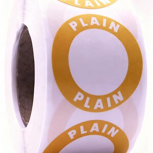 May include: A roll of white stickers with a yellow circular border and the word "PLAIN" printed in the centre. The stickers are rolled up, showing the edges of the individual stickers.