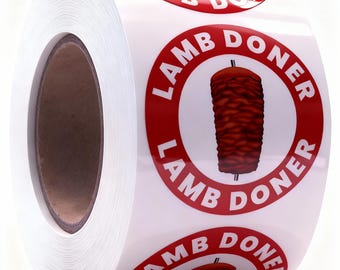 Puede incluir: Un rollo de etiquetas adhesivas circulares con un borde rojo y el texto LAMB DONER en letras mayúsculas blancas. En el centro de cada etiqueta hay una ilustración gráfica de un asador vertical con carne cocinada en un pincho metálico.